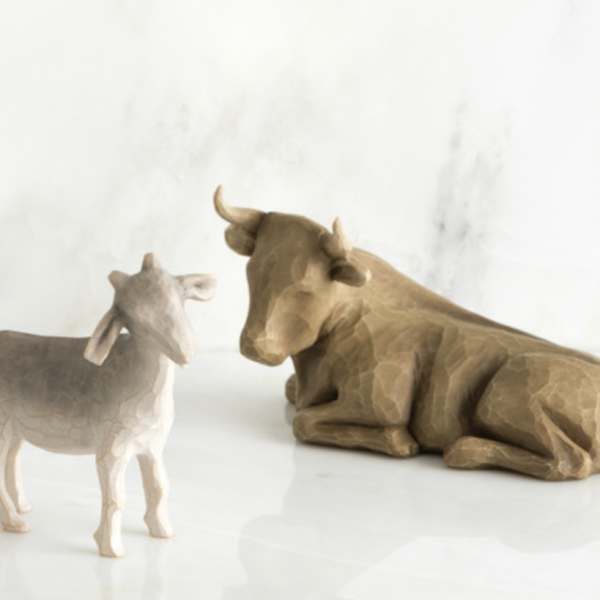Two carved cow figurines on a white surface