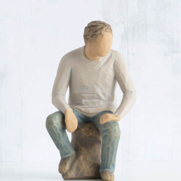 Wooden figurine of a seated person on a rock