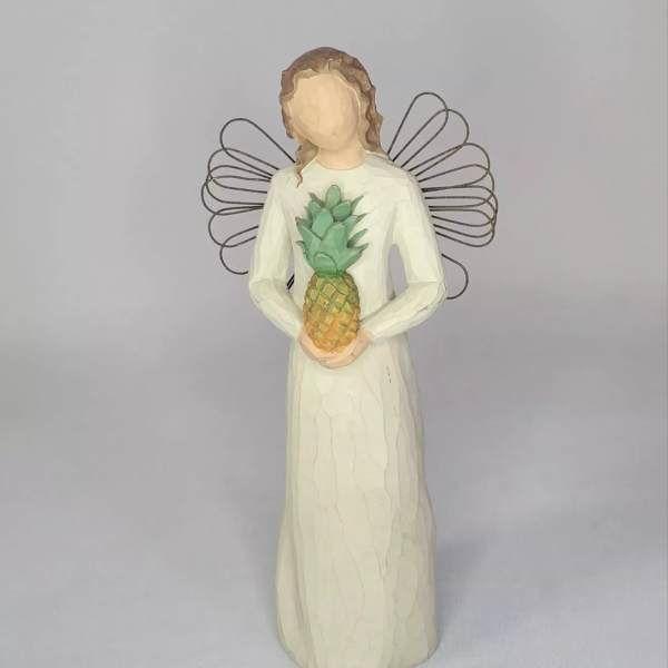 Angel figurine in a white dress holding a pineapple