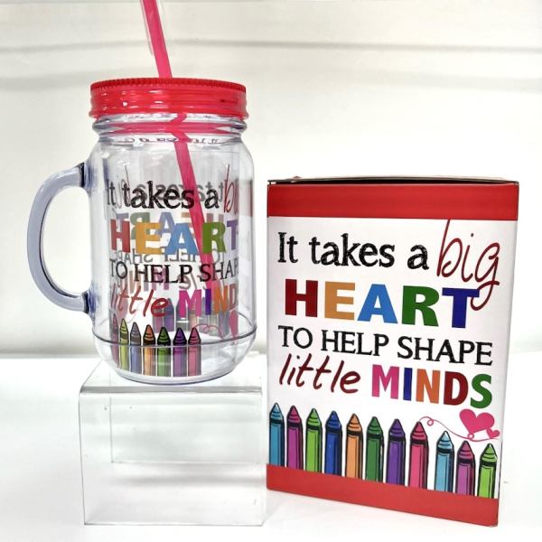 Clear handled tumbler with pink straw beside a gift box with teacher message