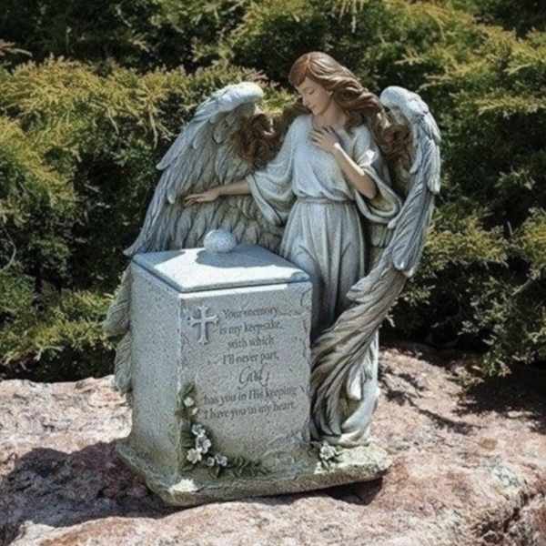 Angel statue beside a memorial stone in a garden