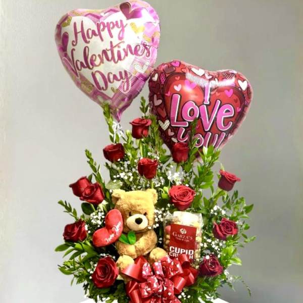Rose arrangement with heart balloons, teddy bear, and candy in a basket