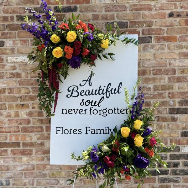 Standing sympathy sign with colorful floral sprays and memorial text