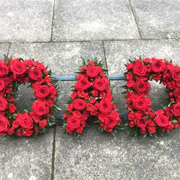 Red rose floral letters spelling "DAD" on pavement