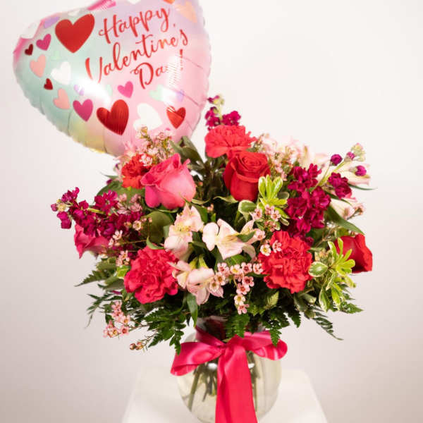 Pink and red flower arrangement with a heart-shaped Valentine balloon in a glass vase