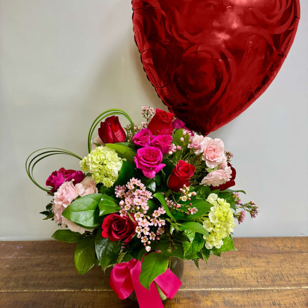 Mixed rose bouquet in a vase with a red heart balloon