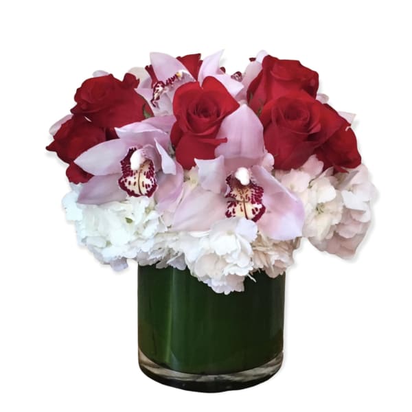 Red roses and pale pink orchids in a green glass vase
