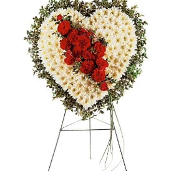 Heart-shaped standing floral spray of white blooms with red flowers on a metal easel.