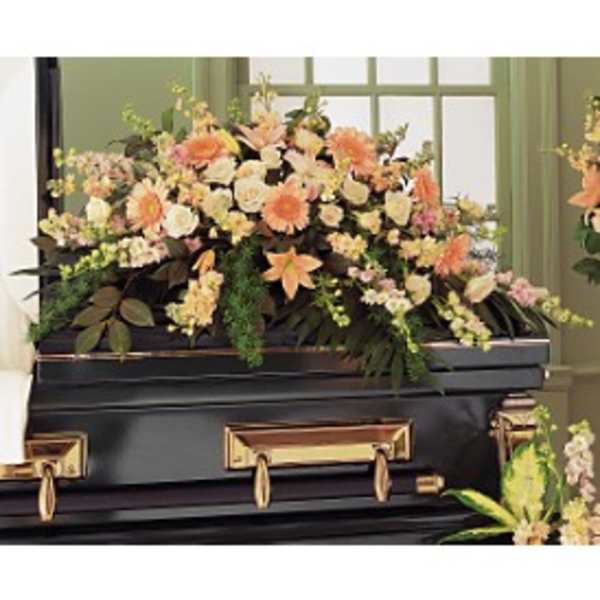 Peach and cream casket spray of lilies, roses, and daisies on a black casket