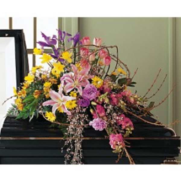Colorful casket spray of pink lilies, yellow daisies, and mixed blooms on a black casket