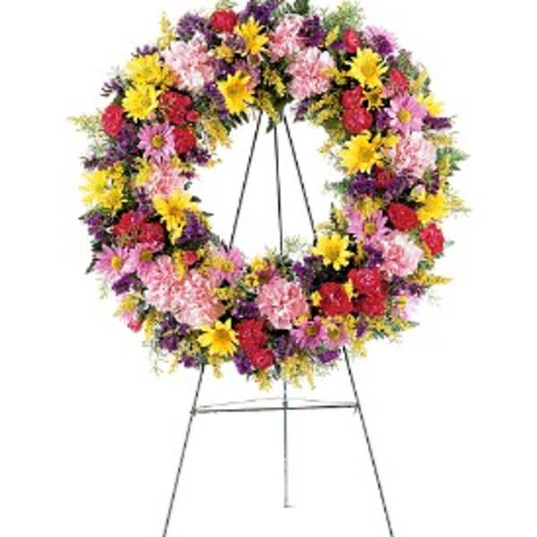 Colorful standing wreath of yellow, pink, red, and purple flowers on a metal easel