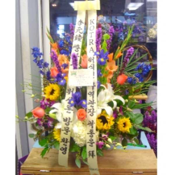 Tall mixed flower arrangement with sunflowers, lilies, roses, and irises with vertical message ribbons
