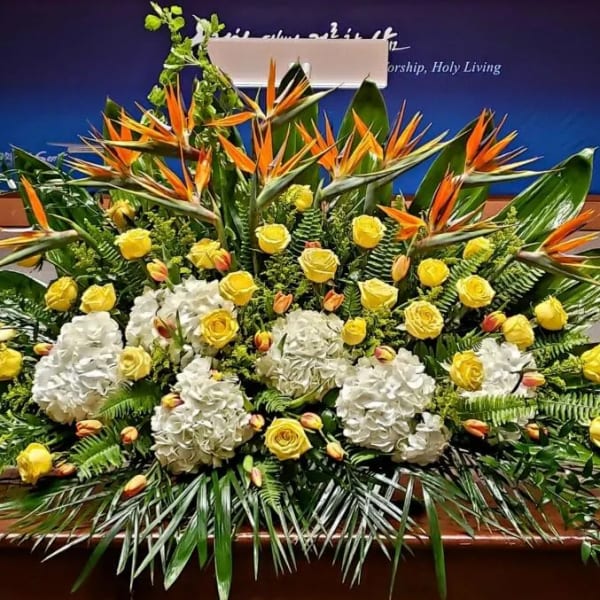 Large yellow and white floral stage arrangement with birds of paradise and tropical foliage