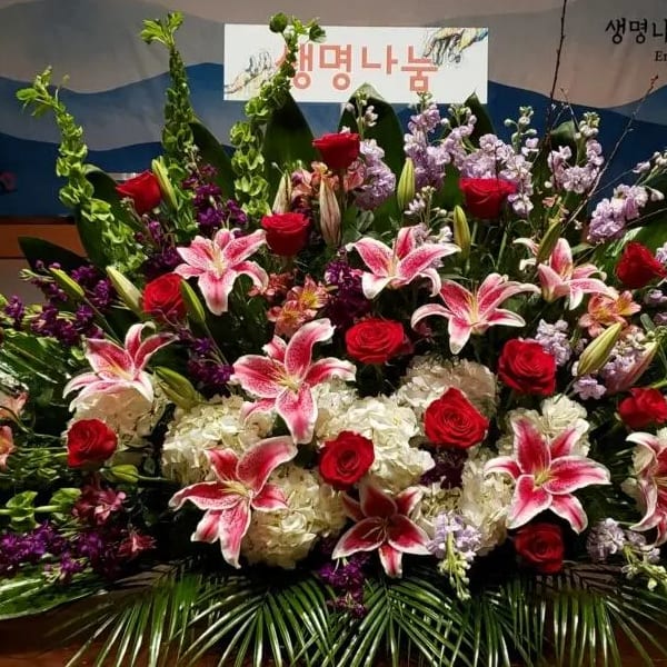 Large altar-style arrangement with pink lilies, red roses, white hydrangeas, and purple flowers