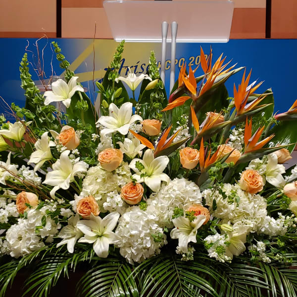 Large stage arrangement of white lilies, peach roses, Birds of Paradise, and white hydrangeas