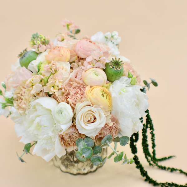 Pastel bouquet of roses, ranunculus, and peonies in a metallic vase
