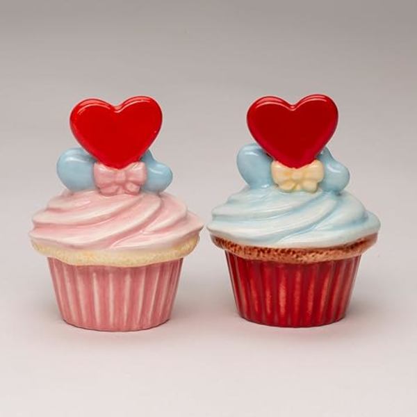 Two decorated cupcakes with heart toppers on a plain background