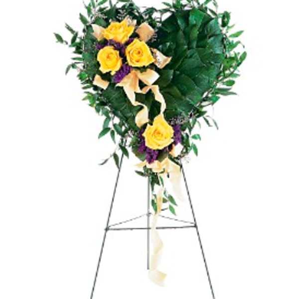 Heart-shaped leafy standing arrangement with yellow roses and ribbon on a metal easel