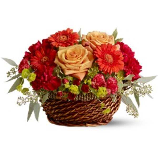 Low basket arrangement with peach roses, orange gerberas, red carnations, and green accent blooms
