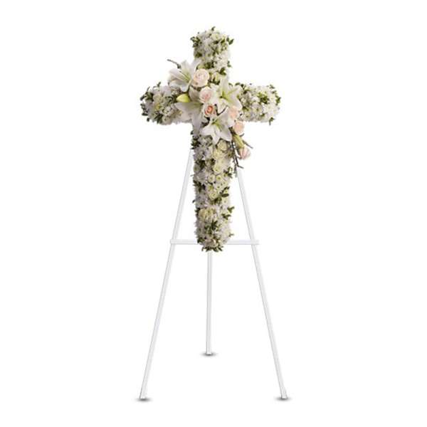 Standing white floral cross with blush roses and lilies on a white easel