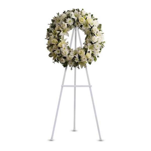 White floral wreath on a tall white easel stand