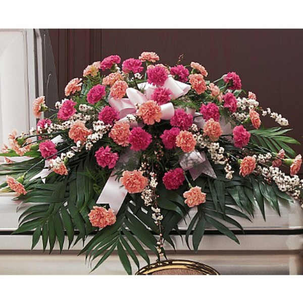 Pink and peach carnation casket spray with white ribbon and filler flowers