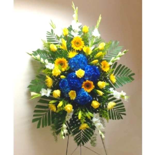 Tall standing spray with blue hydrangeas and yellow blooms on a metal easel