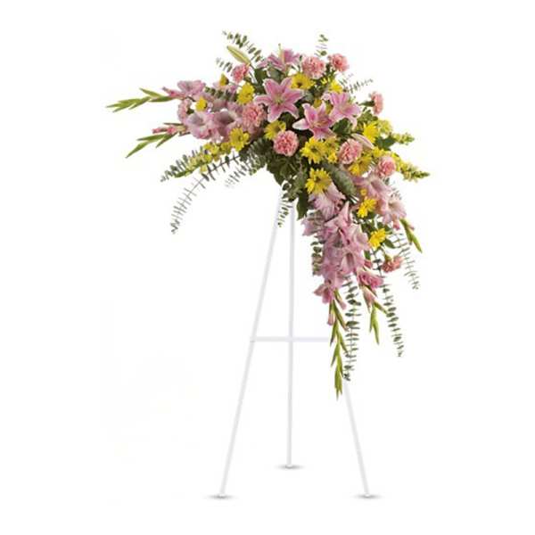 Pink lilies, carnations, and yellow daisies in a cascading standing spray on a white easel