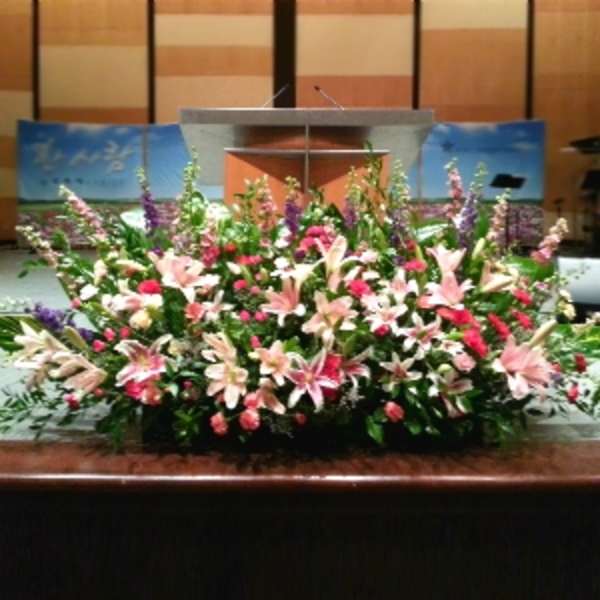 Large stage arrangement of pink lilies and red flowers in front of a podium