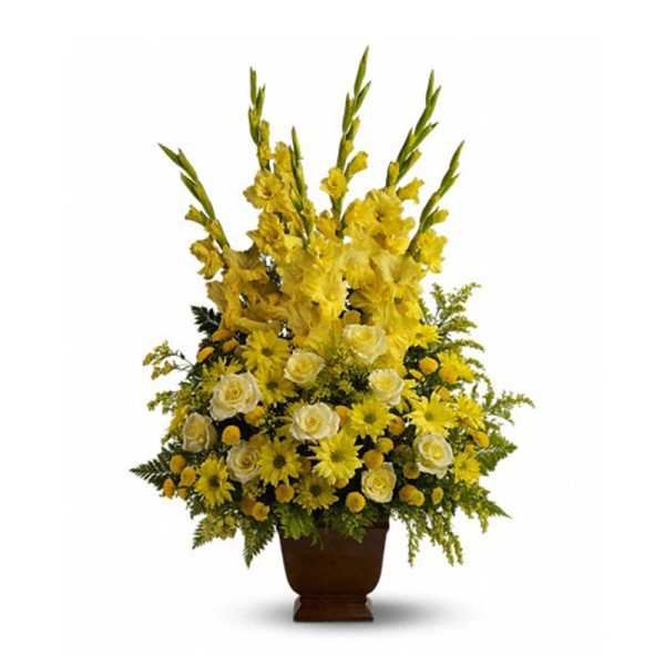 Tall yellow and white funeral-style flower arrangement in a brown pedestal vase