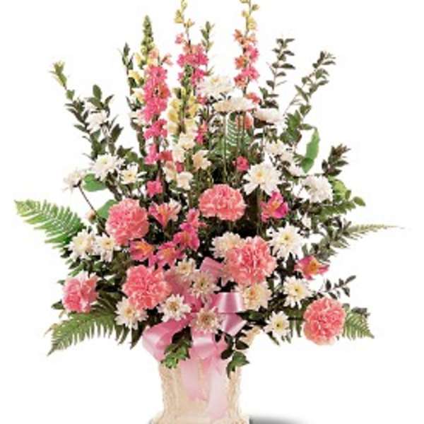 Tall pink and white carnations and daisies in an ivory vase with a pink ribbon bow