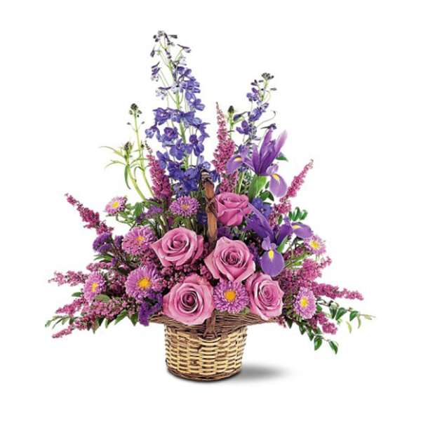 Basket arrangement of pink roses, purple irises, blue delphinium, and asters