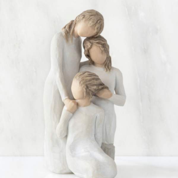 Three faceless figurines in white clothing posed closely together