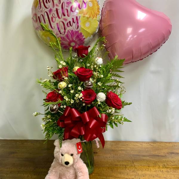 Red roses in a vase with a Mother’s Day balloon, pink heart balloon, and teddy bear