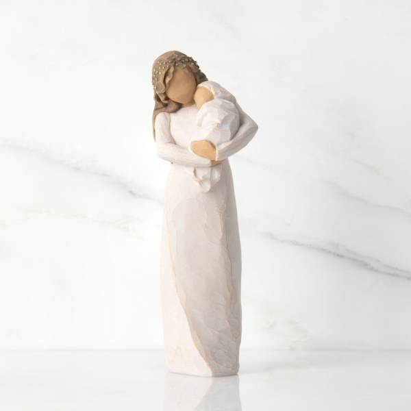 Figurine of a woman holding a baby in a long white dress