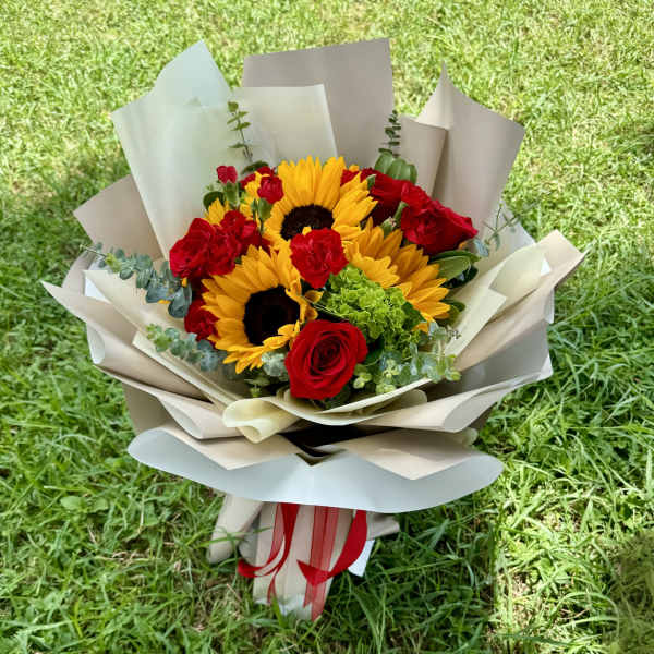 Bouquet of sunflowers and red roses wrapped in beige paper