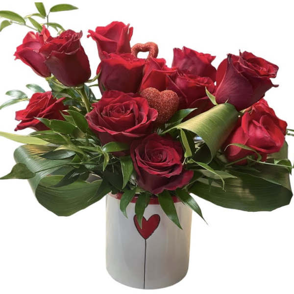 Red roses arranged in a white vase with a heart design