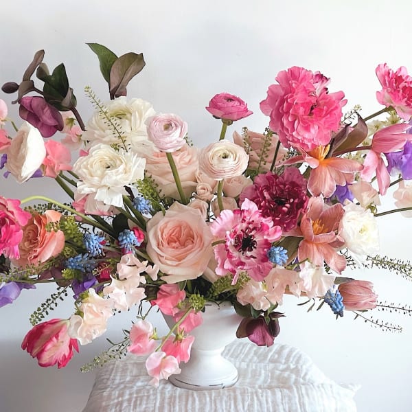 Pastel floral arrangement in a white vase with pink, purple, and white blooms