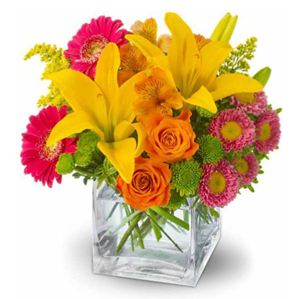 Bright mixed bouquet in a clear square glass vase