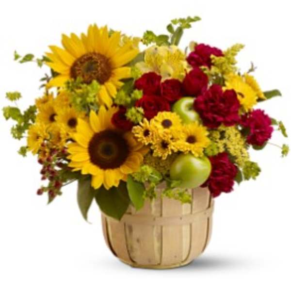 Rustic basket arrangement with yellow sunflowers, red roses, and mixed yellow blooms accented with green apples.