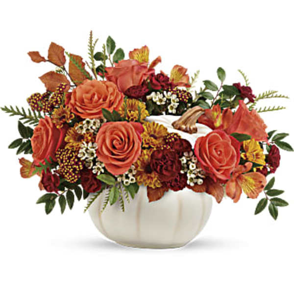 Autumn floral arrangement in a white pumpkin vase with orange and burgundy blooms