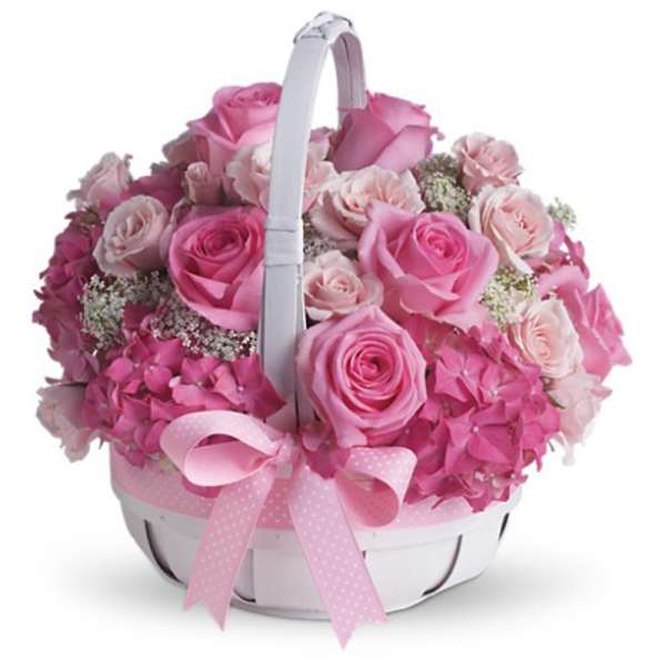 Round white basket filled with pink roses and hydrangeas, finished with a pink ribbon bow.