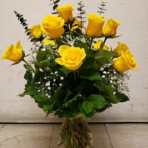 Yellow roses arranged in a clear glass vase with baby's breath