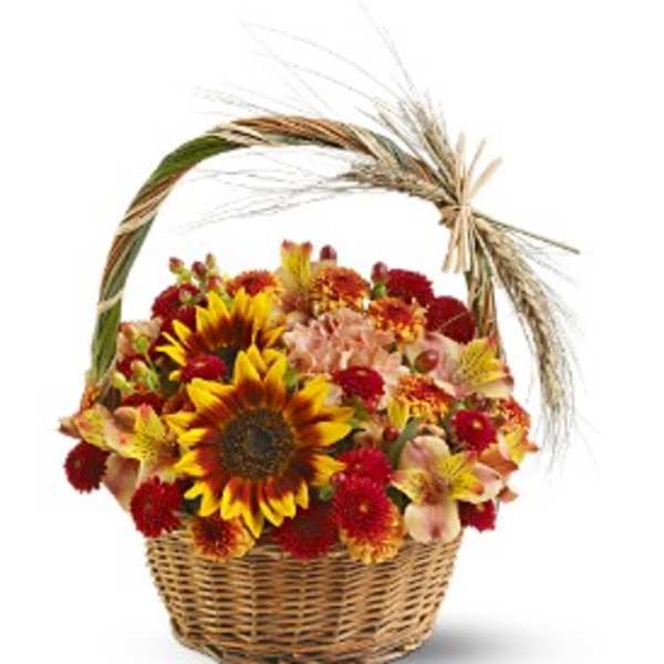 Basket of yellow sunflowers, red mums, and peach flowers with a decorative wheat accent.