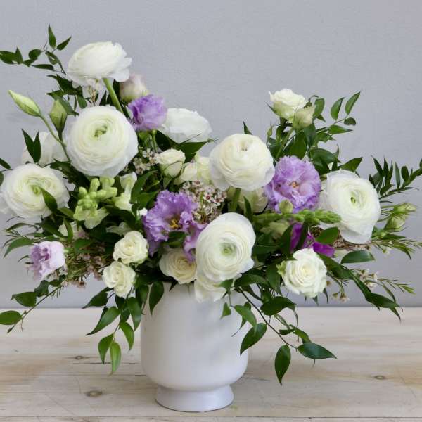 White and light purple flower arrangement in a matte white vase