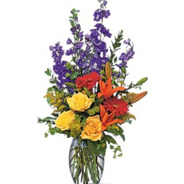 Mixed bouquet of purple, yellow, and orange flowers in a glass vase