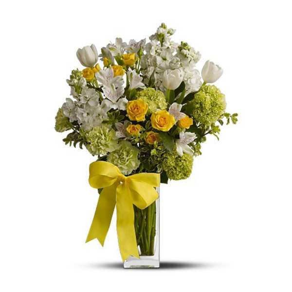 Yellow roses and white flowers in a clear glass vase with a yellow ribbon