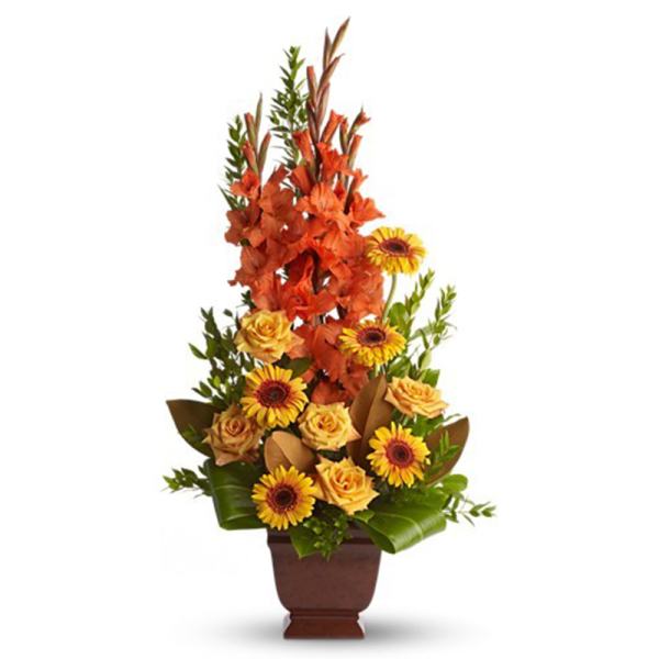 Tall arrangement of orange flowers, yellow roses, and yellow gerbera daisies in a brown vase