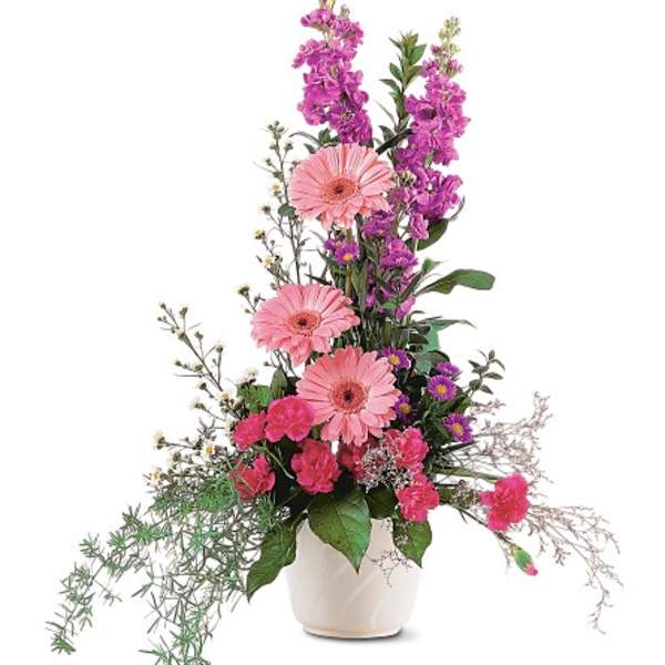 Tall pink and purple flower arrangement with gerbera daisies and carnations in a white ceramic pot