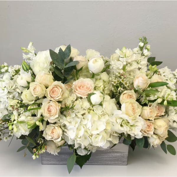 Low white and cream flower arrangement with roses and hydrangeas in a rectangular wooden box